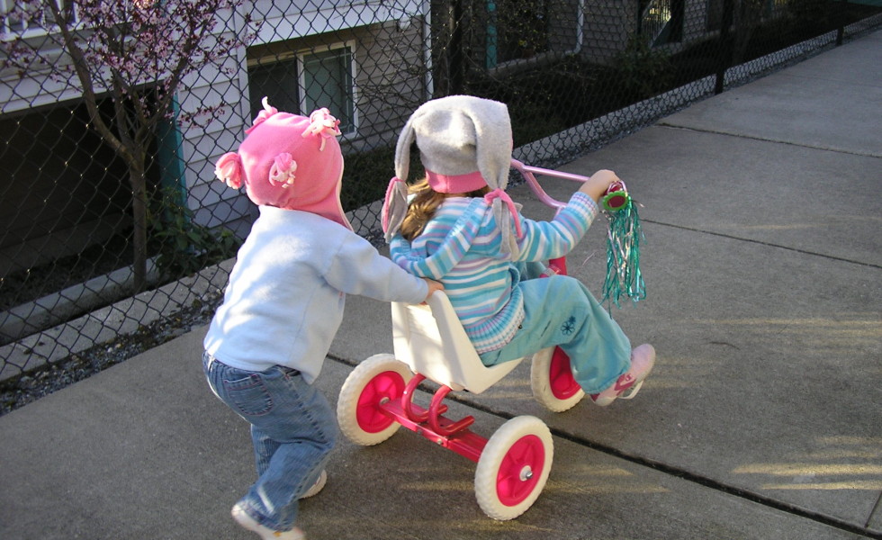 Child pushing child on trike